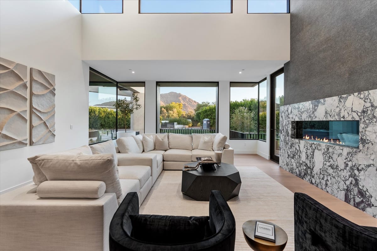 Great room with stone fireplace and mountain views through floor-to-ceiling glass